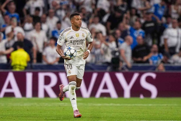 Kylian Mbappé läuft im Trikot von Real Madrid mit dem Ball über den Rasen.