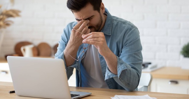 Mann sitzt vor Computer, reibt sich die Augen | Credit: fizkes/Shutterstock
