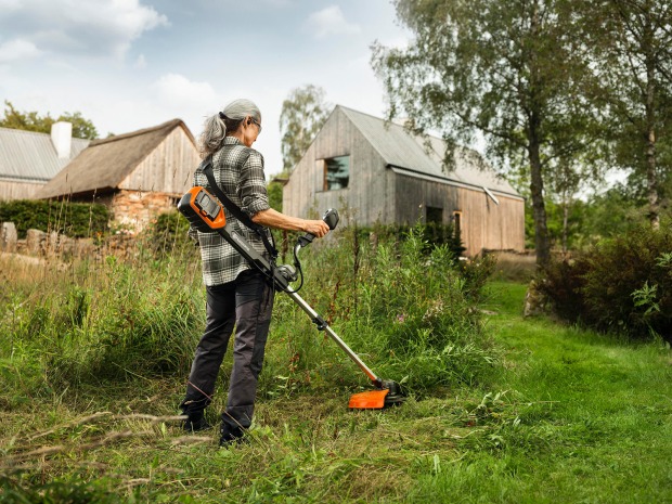 Frau beim Rasentrimmen im Garten | Credit: Husqvarna
