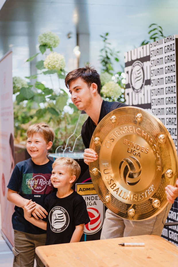 Stefan Hierländer mit zwei kindlichen Fans, der den goldenen Meisterteller der österreichischen Fußball-Bundesliga in die Höhe hält