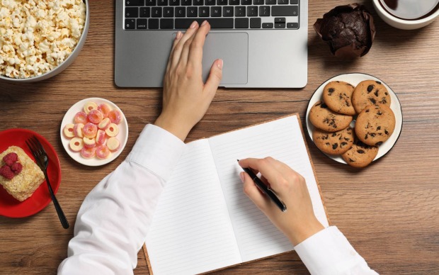 Arbeitsbereich umgeben von Snacks | Credit: New Africa/Shutterstock