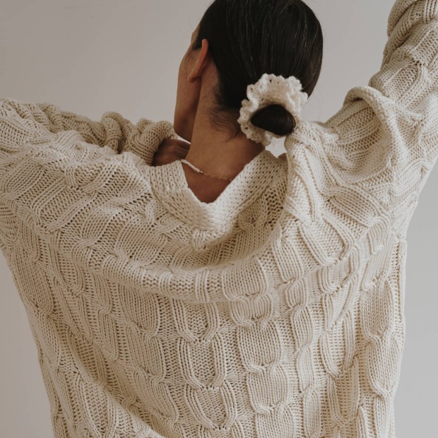Frau in einem weißen Strickpullover / Credits: Floral Deco/Shutterstock