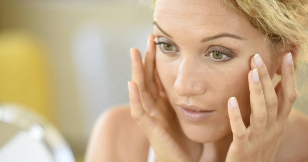 blonde Frau vor einem Spiegel | Credit: goodluz/Shutterstock