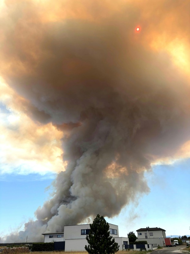 Dichter Rauch über einer Siedlung beim Waldbrand in St. Egyden, die Sonne ist durch die Rauchwolke sichtbar.