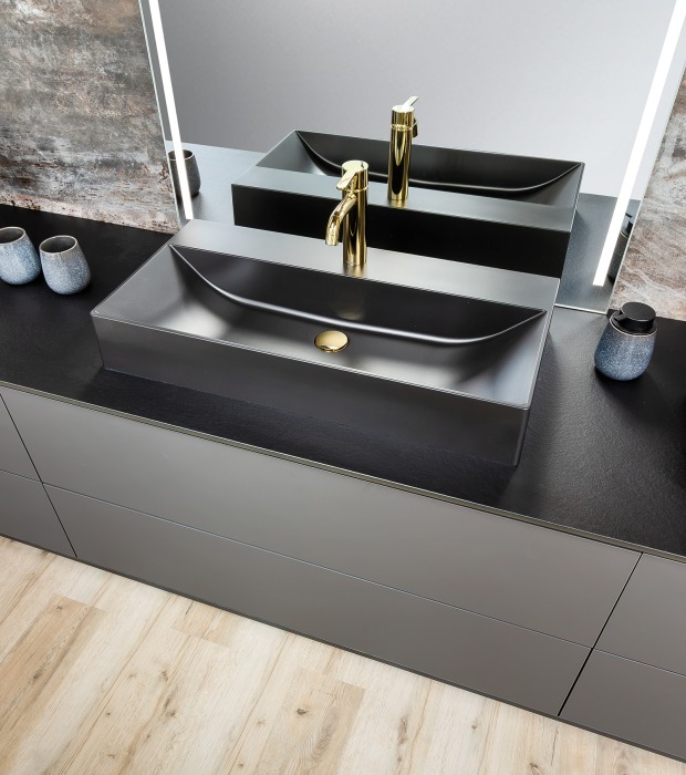 Edles schwarzes Waschbecken im Badezimmer mit vergoldeten Armaturen | Credit: P.MAX