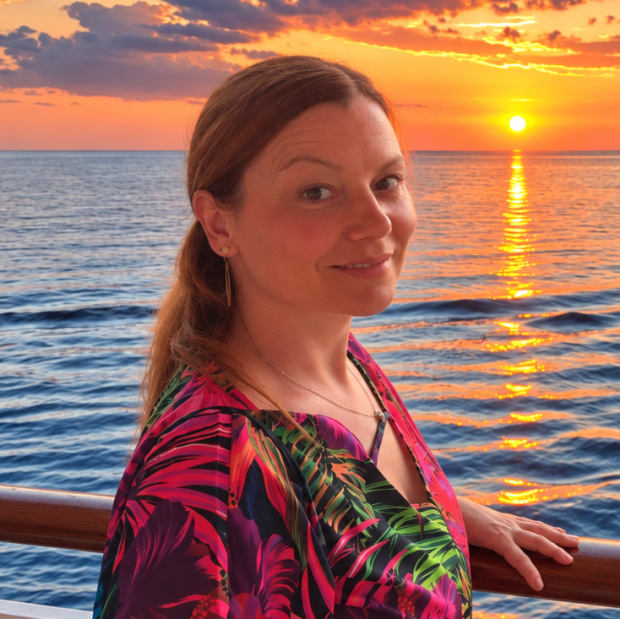 Autorin Alexandra Kulterer vor dem Meer bei Sonnenuntergang auf einem Kreuzfahrtschiff.