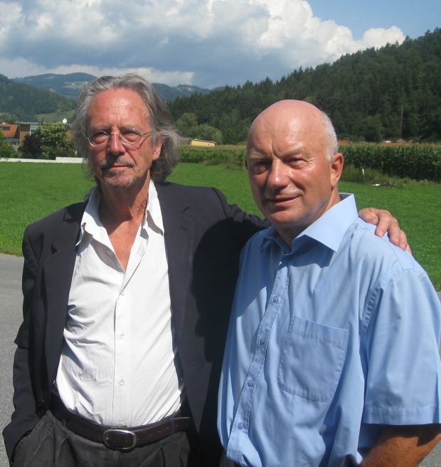 Die Autoren Peter Handke und Valentin Hauser vor einer grünen Wiese mit Waldstück im Hintergrund