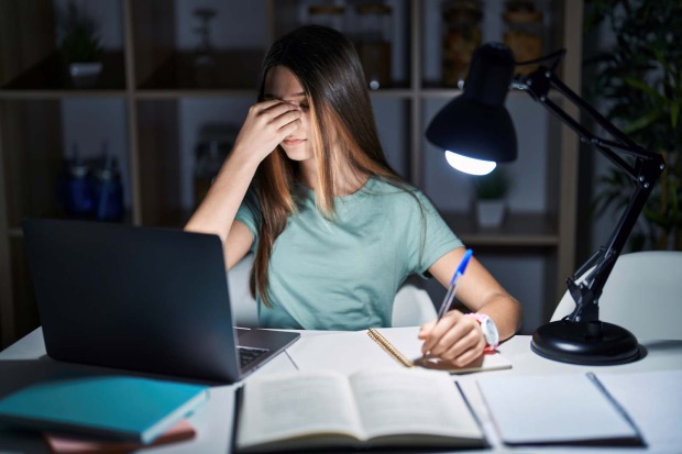 Schülerin lernt abends am Laptop und wirkt erschöpft