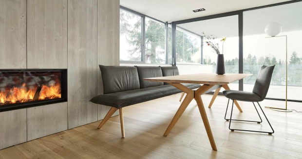Heller Holztisch mit dunklen Sitzmöbeln im Essbereich von Haider Wohnen