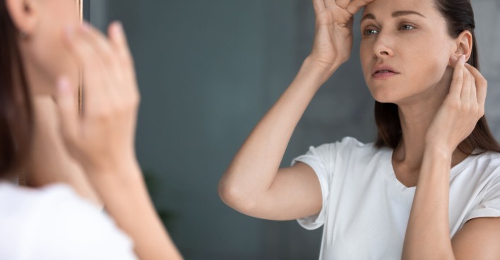 Frau sucht ihr Spiegelbild nach Falten ab