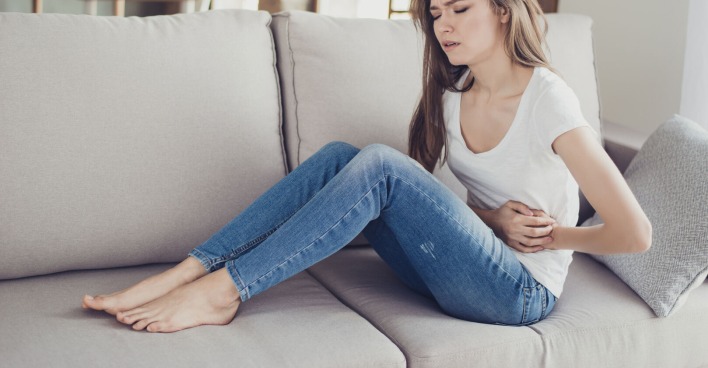 Frau mit Bauchschmerzen auf Sofa
