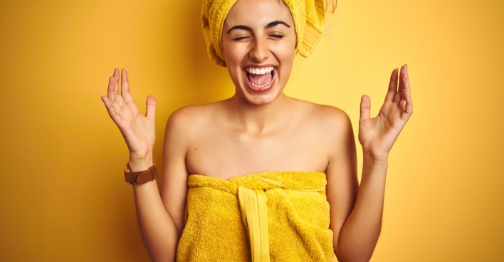 Eine lachende junge Frau mit Badehandtuch und Handtuchturban