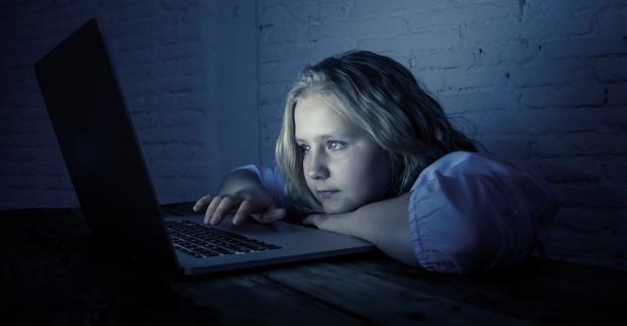 Kind starrt gebannt auf den Bildschirm eines Laptops