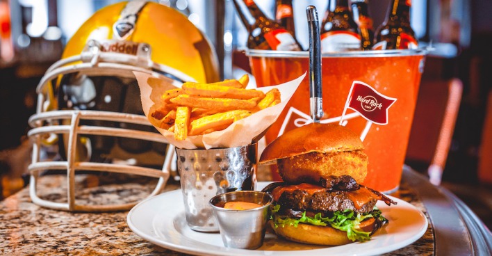 Ein Football-Helm, ein Burger mit Pommes und ein Kühler mit Bierflaschen