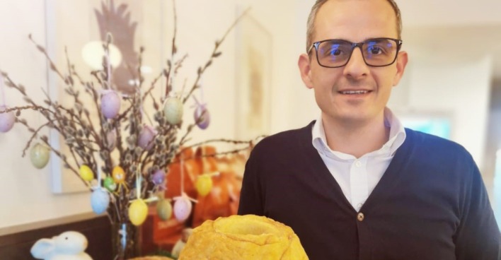 Bäckermeister Taumberger mit zwei Osterreindlingen in den Händen vor einem osterlich dekorierten Tisch