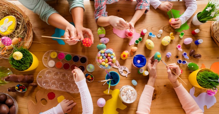 Eine Vogelperspektive auf einen Tisch, an dem Kinder mit österlichem Bastelmaterial spielen