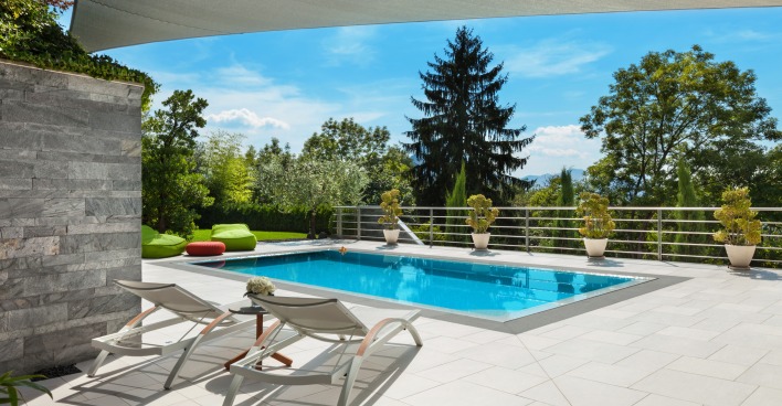 Ein Swimmingpool auf einer Steinterrasse mit Blick auf einen Wald