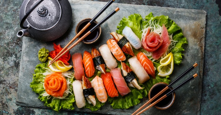 Eine Sushiplatte mit Essstäbchen, Schalen für die Sojasauce und einem Teekessel