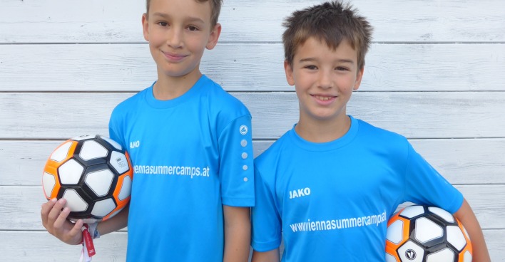Zwei Buben mit blauem Shirt mit einem Fußball