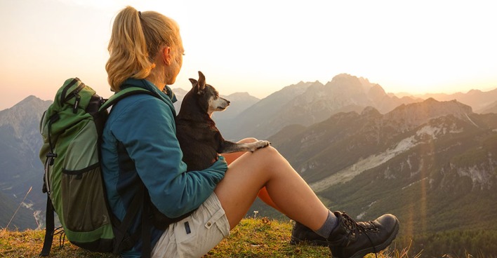 Frau und Hund machen Pause beim Wandern. Credit: iStock.com/helivideo