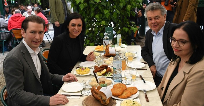 (v.l.) Bundeskanzler Sebastian Kurz (ÖVP), Landwirtschaftsministerin Elisabeth Köstinger (ÖVP), Vizekanzler Werner Kogler (Grüne) und Staatssekretärin Andrea Mayer (Grüne) sizen im Schweizerhaus an einem Tisch mit Stelze, Beilagen und Mineralwasser.