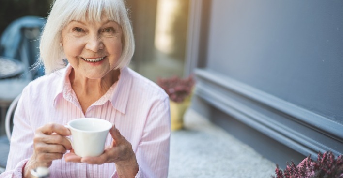 Attraktive ältere Dame hält eine Tasse Kaffee in der Hand