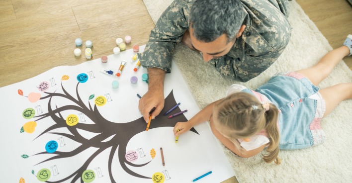 Vater und Tochter am Boden liegend und einen Stammbaum malend