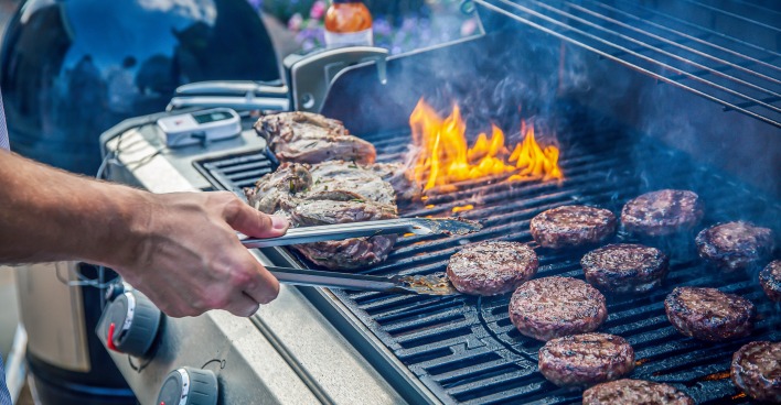 Nahaufnahme eines rauchenden Grills, auf den unterschiedliche Fleischsorten gelegt wurden