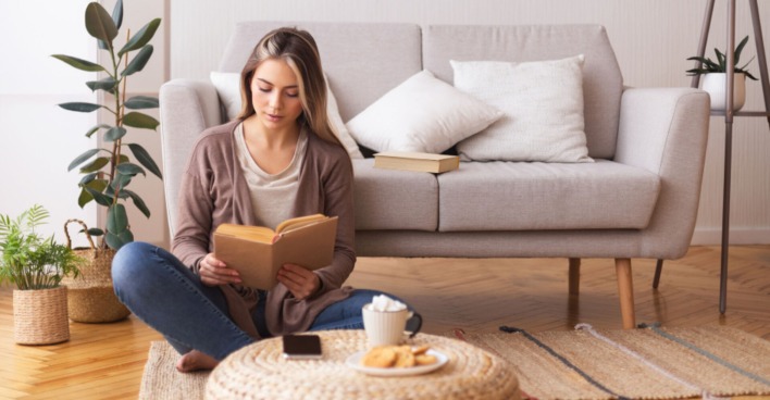 Frau beim Lesen im Wohnzimmer | Credit: iStock.com/Prostock-Studio