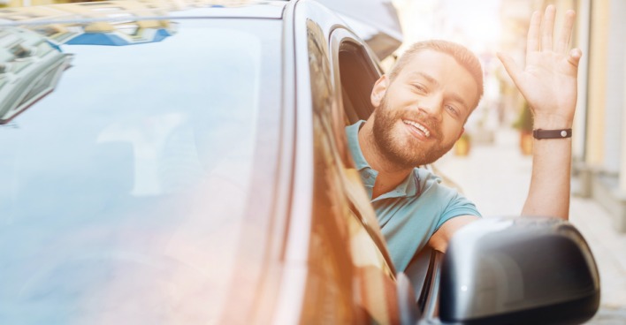 Mann winkt aus dem Auto| Credit: iStock.com/Zinkevych