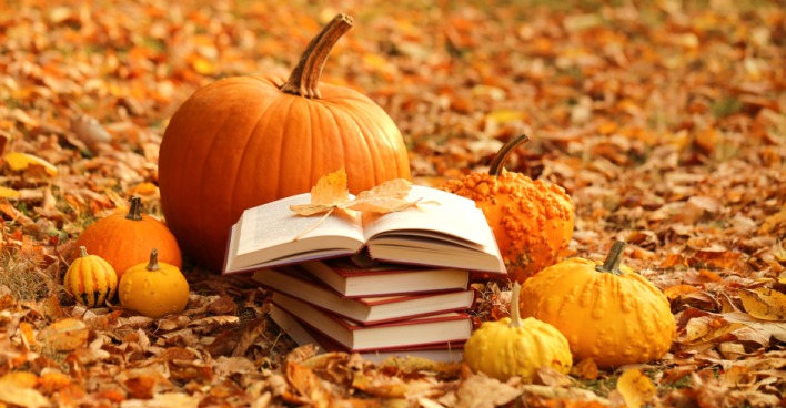 Buchstapel umgeben von Kürbissen und herbstlichen Blättern im Freien | Credit: iStock.com/yul38885