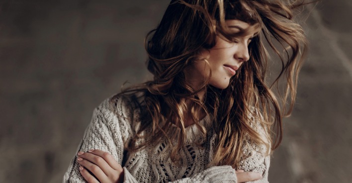 Coole, junge Frau im Wollpullover schüttelt ihr langes Haar | Credit: iStock.com/Bogdan Kurylo