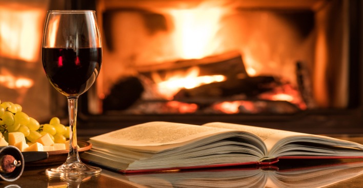 Lesestunde am offenen Kamin mit einem Glas Rotwein | Credit: iStock.com/Rasulovs