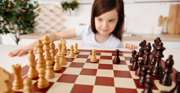 Kleines Mädchen spielt meisterhaft Schach | Credit: iStock.com/yacobchuk