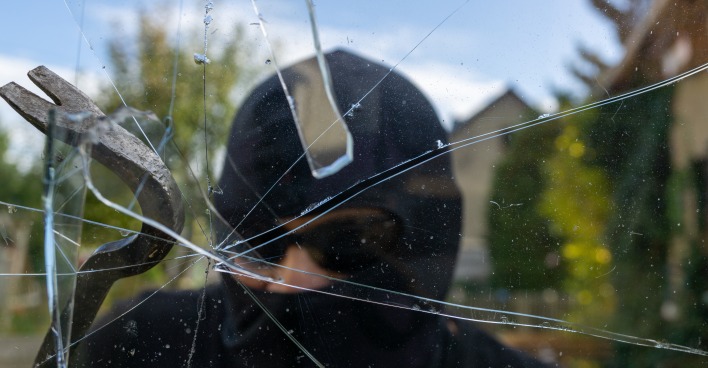 Einbrecher schlägt ein Fenster ein