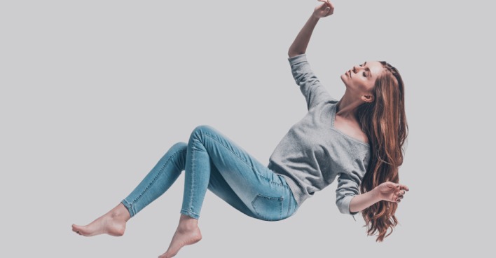 Schwebende Frau in Skinny Jeans und grauem Oberteil | Credit: iStock.com/g-stockstudio