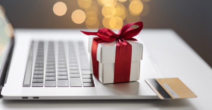 Weihnachtspäckchen und Kreditkarte liegen auf einer Notebook-Tastatur | Credit: iStock.com/Poike