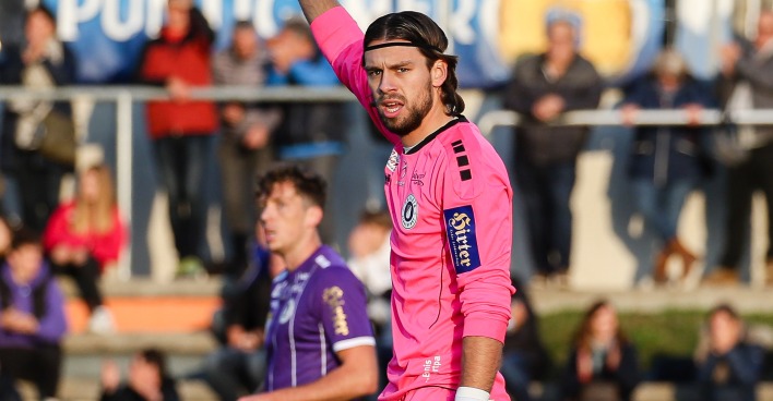 Der Torhüter des SK Austria Klagenfurt, Phillip Menzel, in einer rosaroten Torhütermontur auf dem Spielfeld vor der Zuschauertribüne