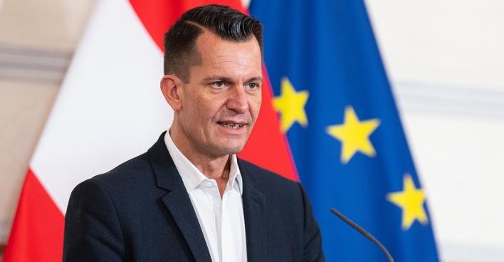 Gesundheitsminister Wolfgang Mückstein bei einer Pressekonferenz vor der Österreichischen und Europäischen Flagge.