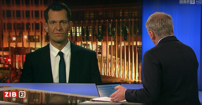 Eine Aufnahme der Sendung Zeit im Bild. Armin Wolf moderiert mit dem Rücken zur Kamera, per Screen zugeschaltet ist Wolfgang Mückstein aus Brüssel