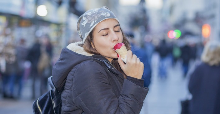 Frau isst im Winter ein Eis auf der Straße