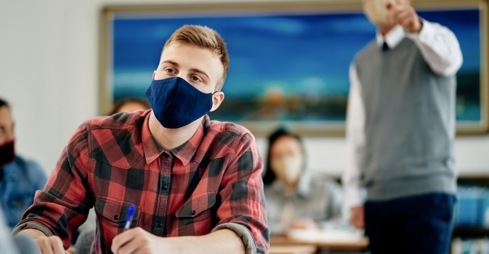 Schüler sitzt mit FFP2-Maske in der Klasse | Credit: iStock.com/Drazen Zigic