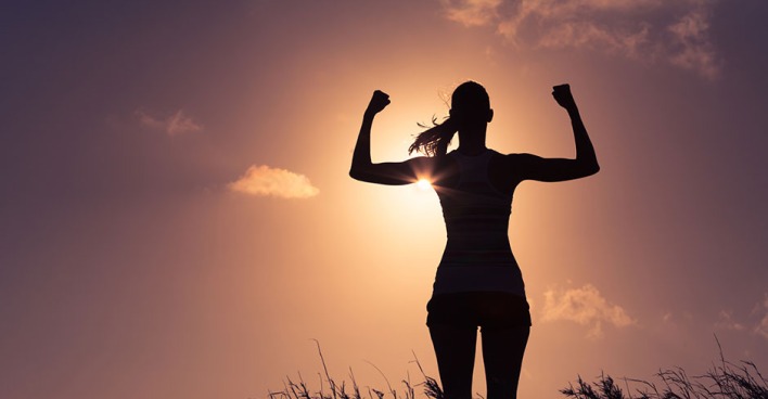 Frau streckt voller Energie ihre geballten Fäuste in die Luft | Credit: iStock.com/kieferpix