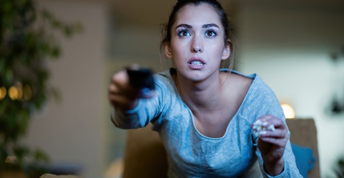 Junge Frau in Hochspannung vor Beginn der Lieblingsserie | Credit: iStock.com/Drazen Zigic
