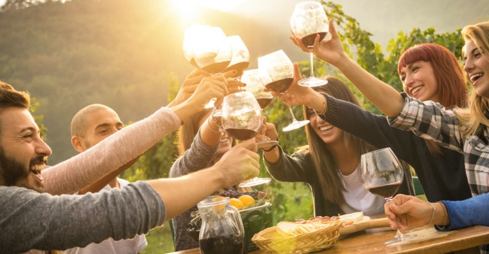 Freunde sitzen an einem Tisch im Weingarten | Credit: iStock.com/ViewApart
