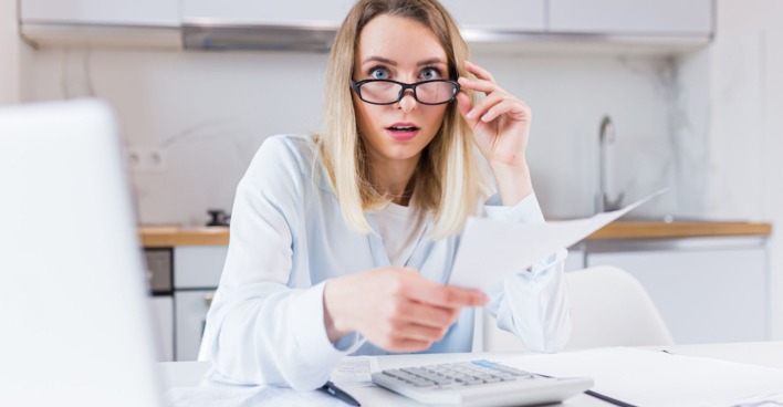 Frau in weißer Bluse mit Brille schaut schockiert | Credit: iStock.com/Liubomyr Vorona