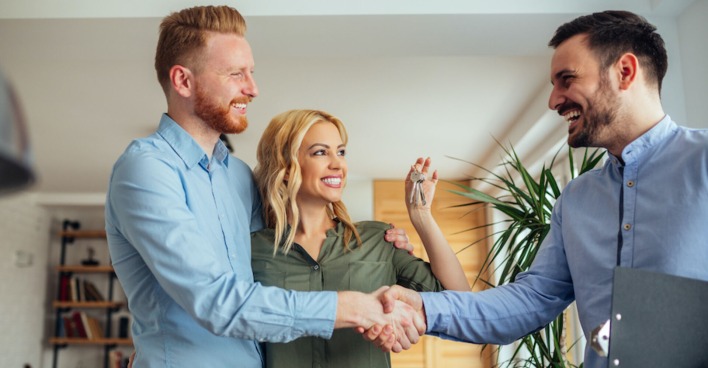 Makler schüttelt einem Mieter und seiner Freundin die Hand | Credit: iStock.com/bernardbodo