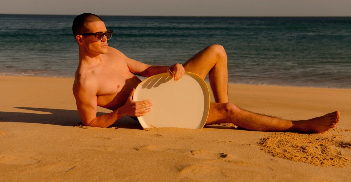 Mann liegt mit Sonnenbrille am Strand