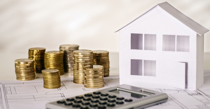Münzen und Taschenrechner mit Papierhaus | Credit: iStock.com/gopixa