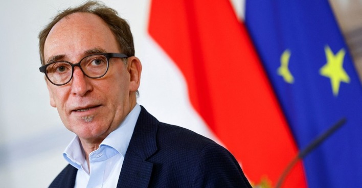 Johannes Rauch mit Brille vor der österreichischen und der europäischen Flagge